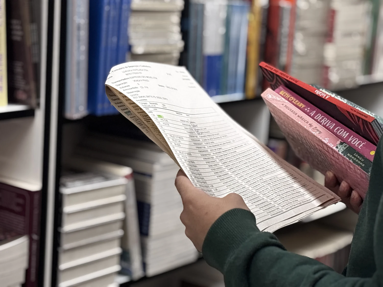Mãos conferindo livros junto ao estoque no CD RS